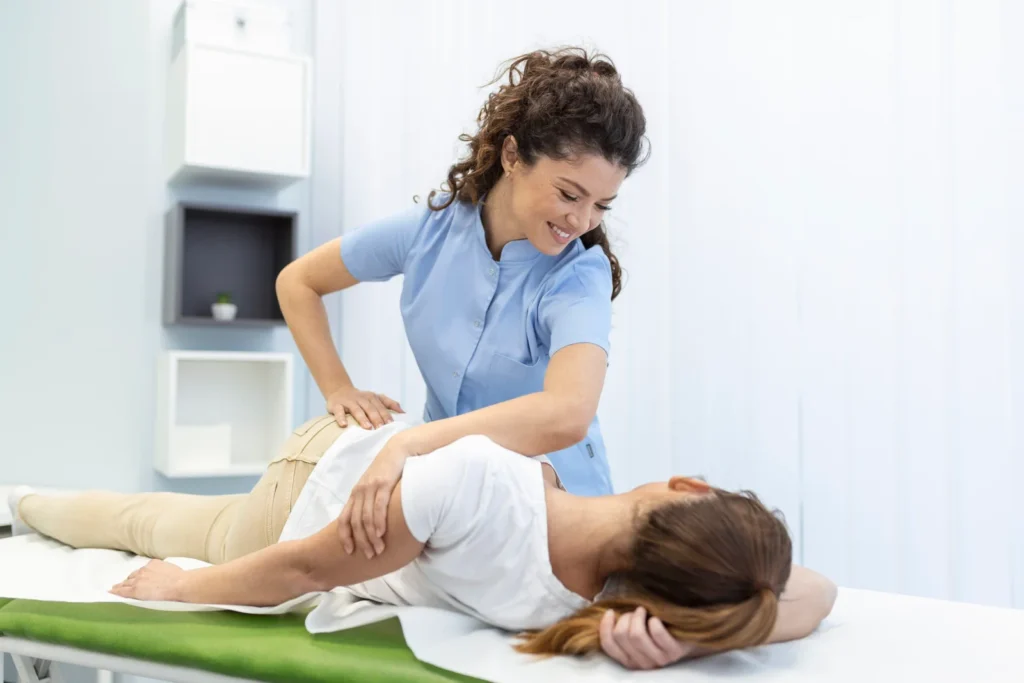 young woman doctor chiropractor osteopath fixing lying womans back with hands movements during visit manual therapy clinic professional chiropractor during work scaled